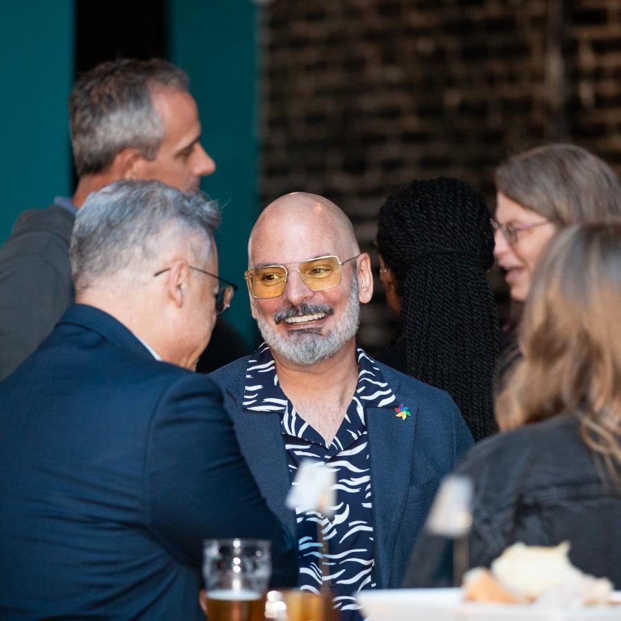 man with glasses talking to people at party