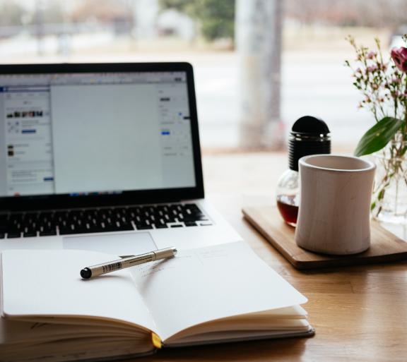 laptop with planner and mug on table