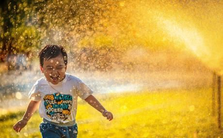 boy playing in sprinkler