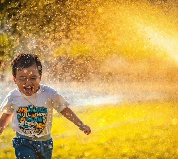 boy playing in sprinkler