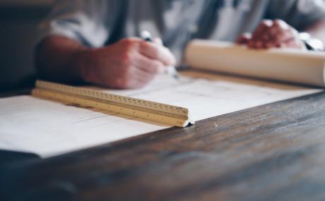 paper on desk with ruler and man's hands