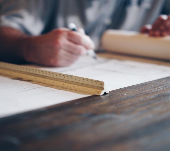 paper on desk with ruler and man's hands