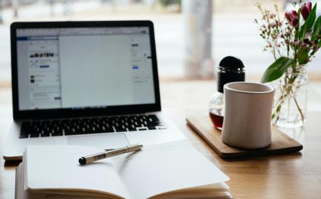 laptop with planner in front and cup of coffee