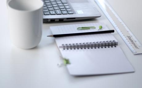 a laptop, planner and mug on a desk