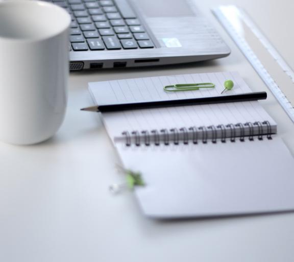 a laptop, planner and mug on a desk